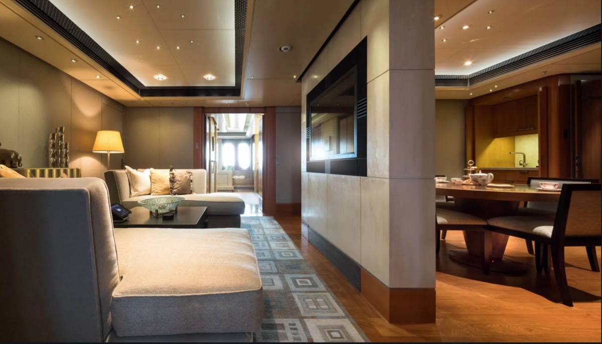 A lounge and dining interior with upholstered seating, wood paneling and a central partition.